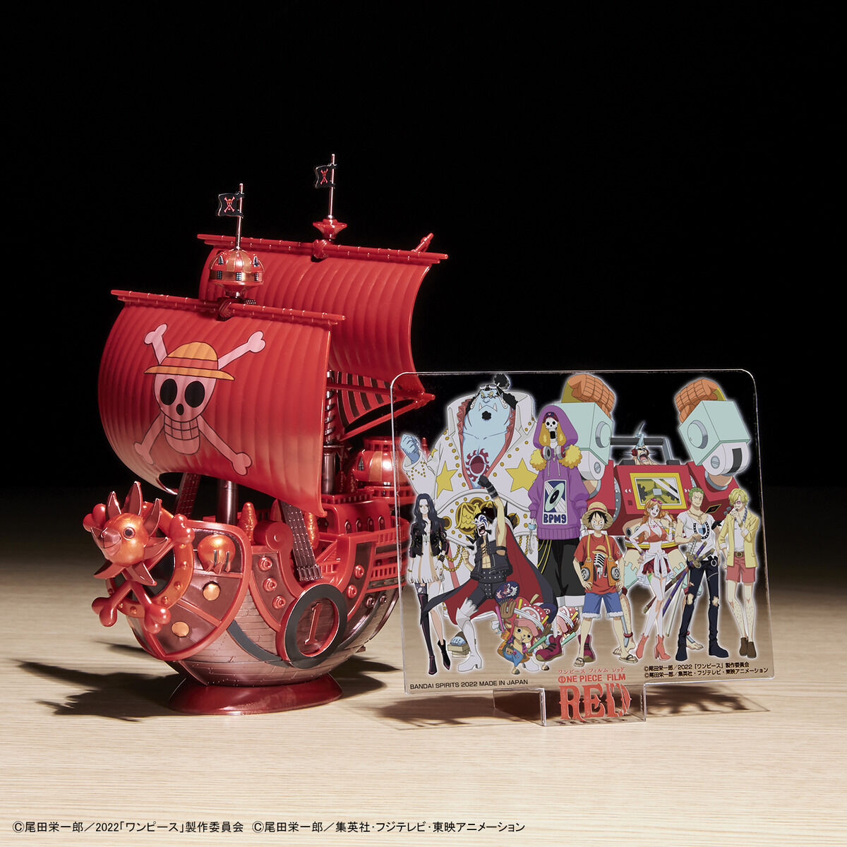 One Piece - Thousand Sunny - RED FILM Special - Grand Ship Collection Model Kit (Bandai), Metallic red color scheme inspired by the film "ONE PIECE FILM RED", includes character plates of the Straw Hat Pirates in movie costumes, display base and sea surface effect included, from Nippon Figures.